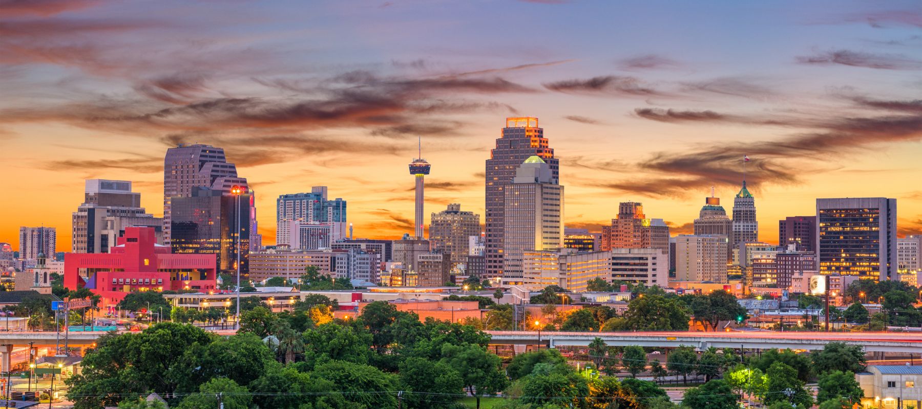 The San Antonio, Texas skyline glows under a colorful sunset with the Tower of the Americas in view